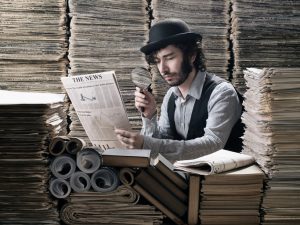 Young man in old fashioned costume doing research among newspapers